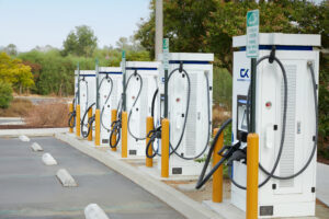 Photo of ChargeTronix Level 3 Apex DC Chargers aligned in a parking lot in the day time.