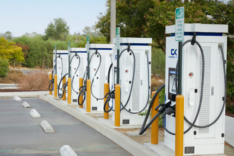 Photo of ChargeTronix Level 3 Apex DC Chargers aligned in a parking lot in the day time.