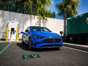 Blue electric vehicle parked at an EV charging station with charging equipment in the background.